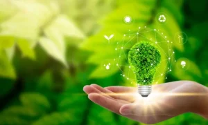 consumo energético más eficiente con mano y bombilla virtual sobre fondo verde, hojas de arboles